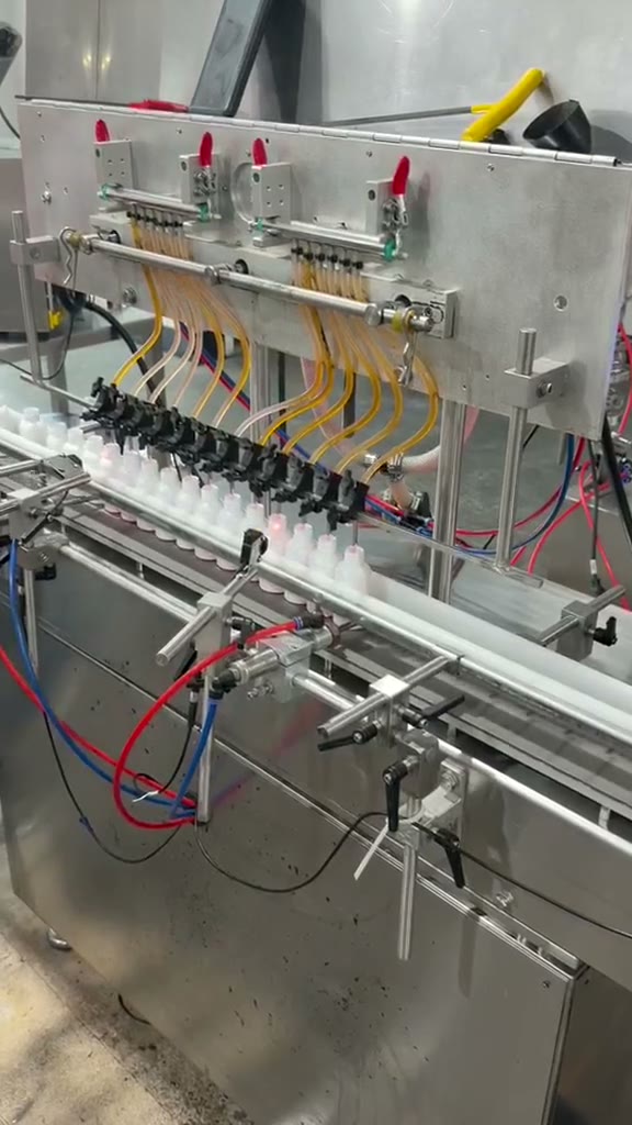 The liquid-shot filling line with bottles moving under the filling heads